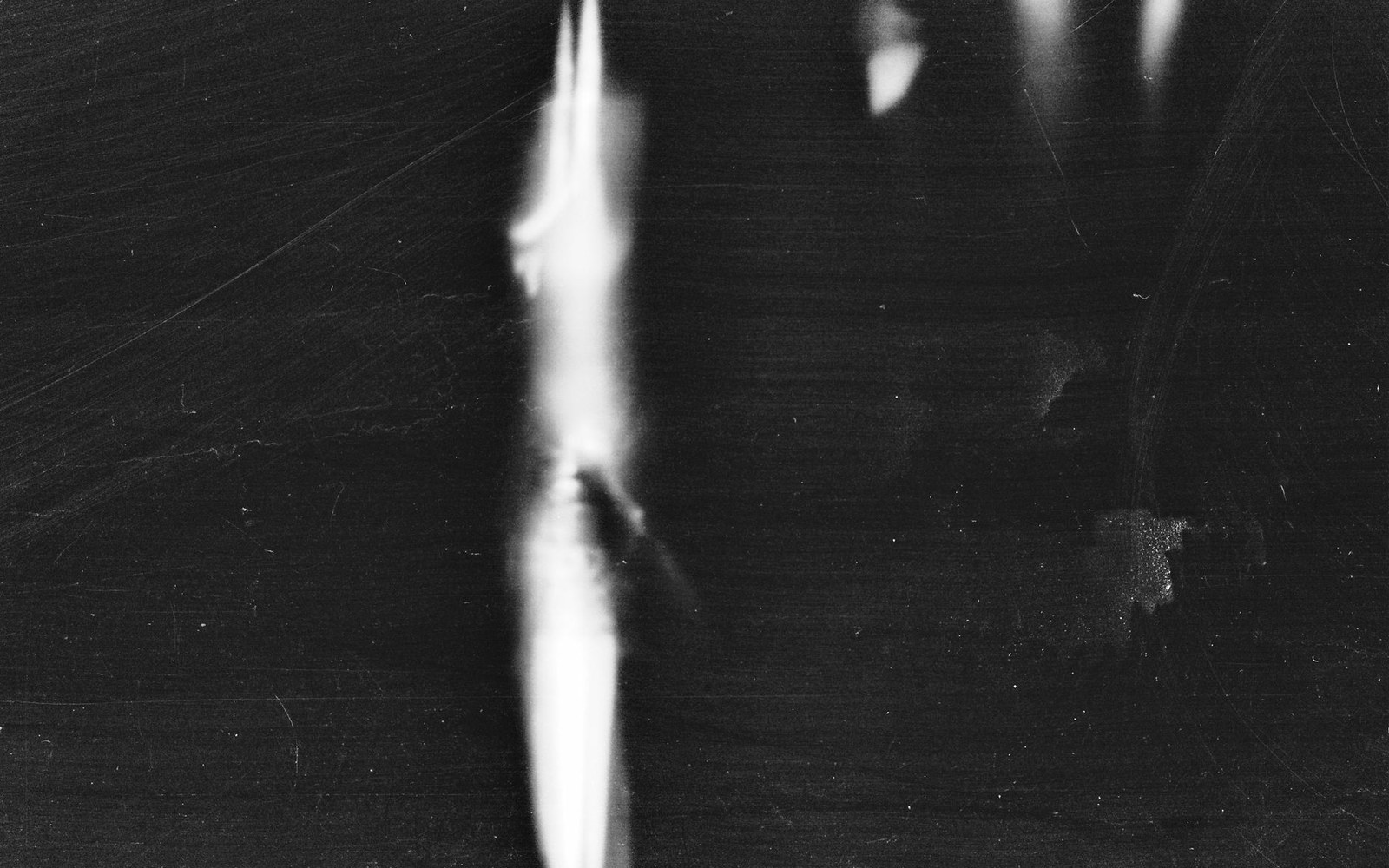 A blurred vertical streak of light against a dark, scratched background