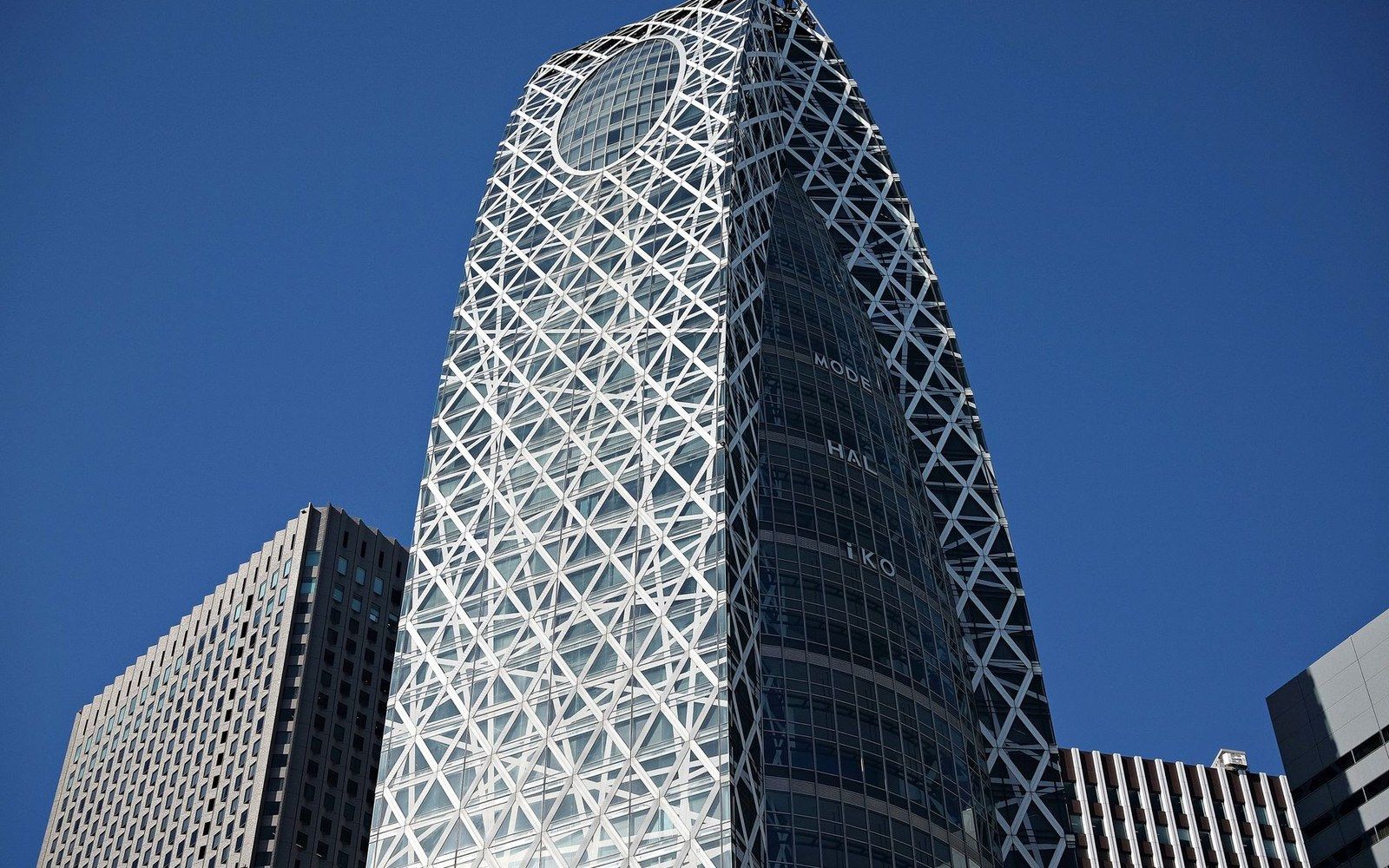 Cocoon-shaped skyscraper with a lattice exterior and circular window against blue sky