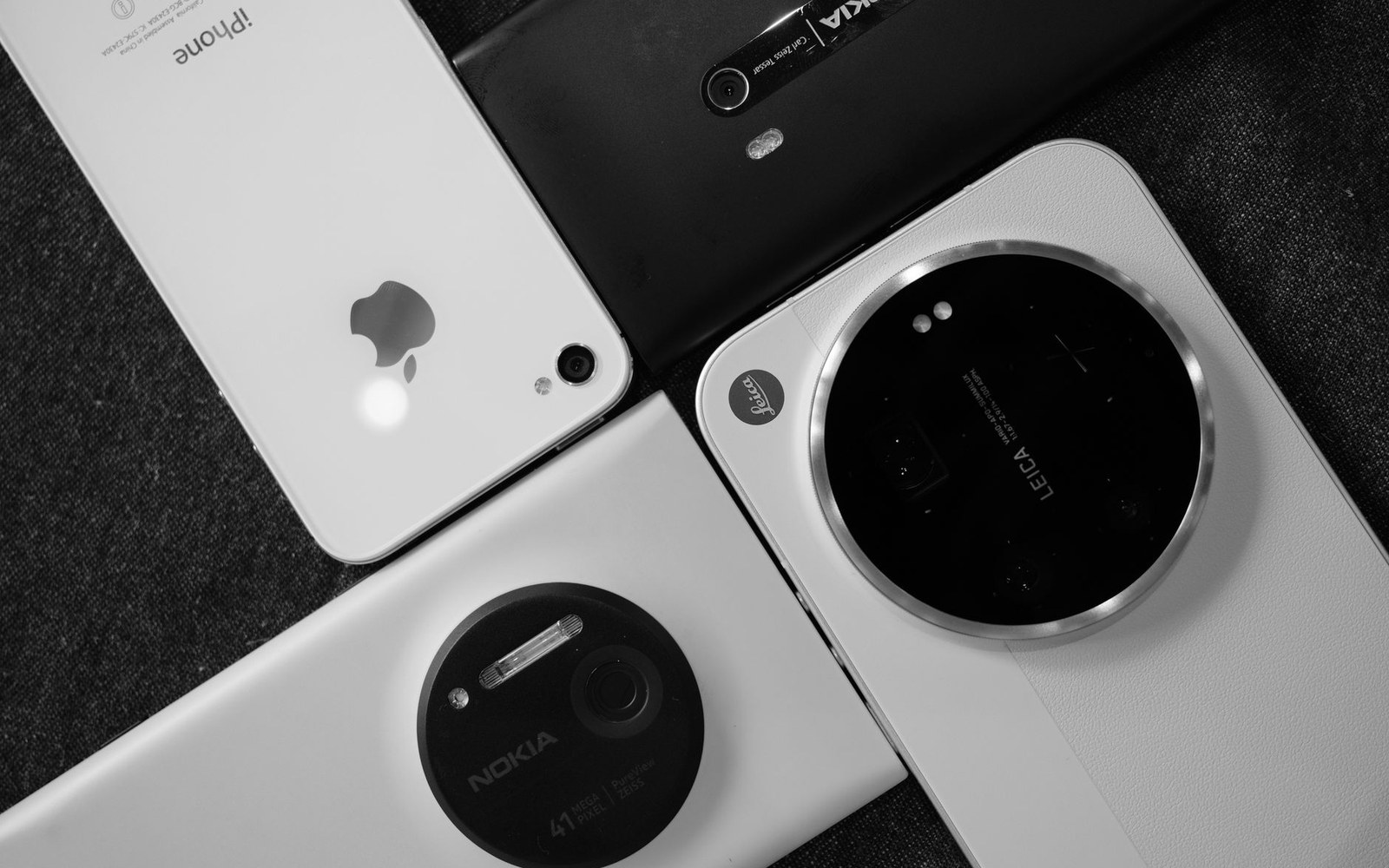 Four smartphones with large camera modules, including Nokia and Leica branding, arranged on a dark surface