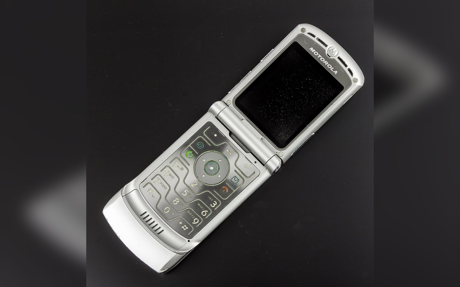 A silver Motorola Razr V3 flip phone open, showing its keypad and small screen