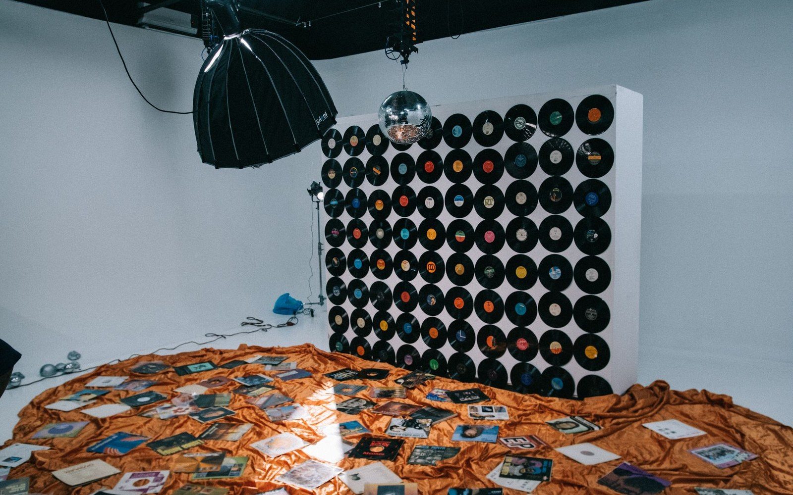 Vinyl records arranged in a grid on a studio wall above scattered album covers
